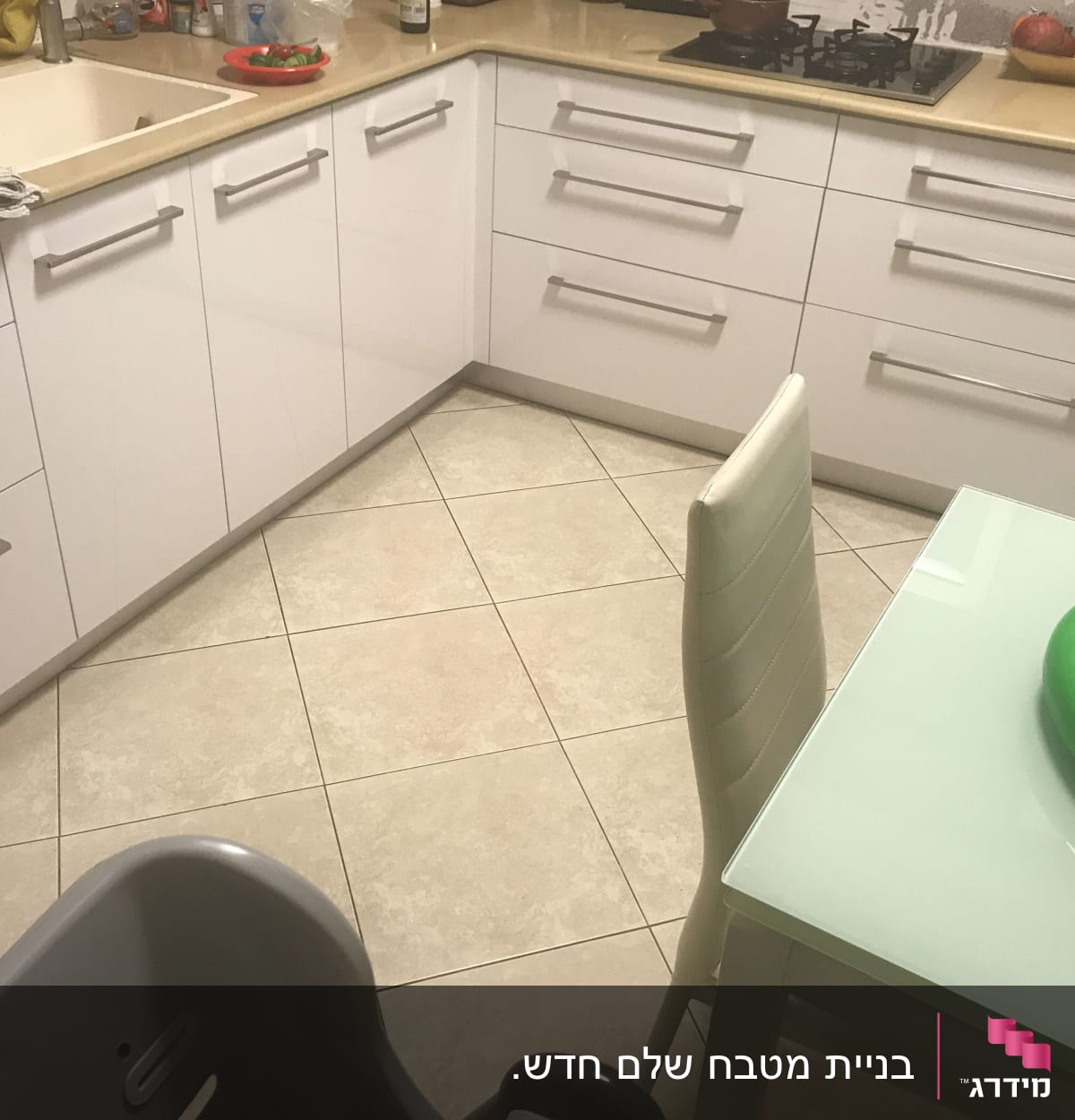 מטבח עם ארונות לבנים, כיור ושולחן זכוכית